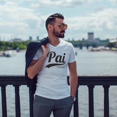 Homem a usar t-shirt branca com texto 'Pai DESDE 2023' junto a uma ponte sobre rio.