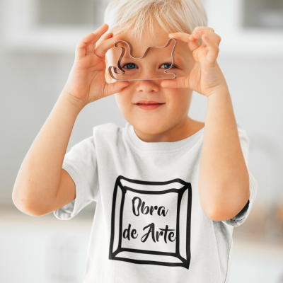 Criança loira com camisola branca 'Obra de Arte' segurando cortador de biscoitos em forma de cachorro