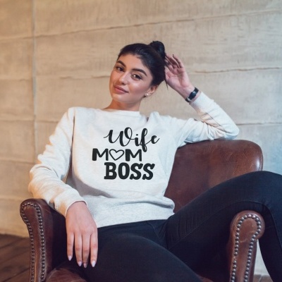 Mulher sentada numa cadeira de couro castanho a usar moletom branco com texto preto