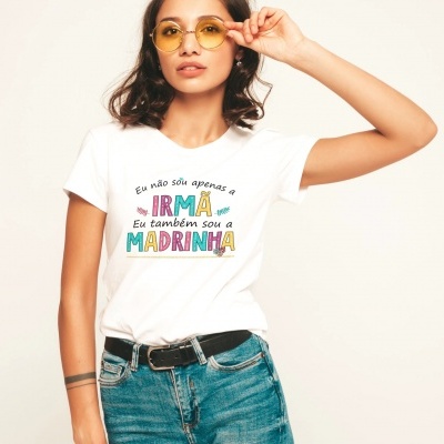 Mulher com t-shirt branca com texto colorido em português, calças de ganga e óculos amarelos.