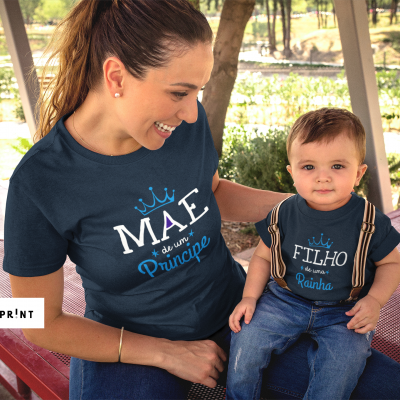 Mãe e filho vestidos com t-shirts azuis escuras com textos relacionados a príncipe e rainha, sentados num parque.