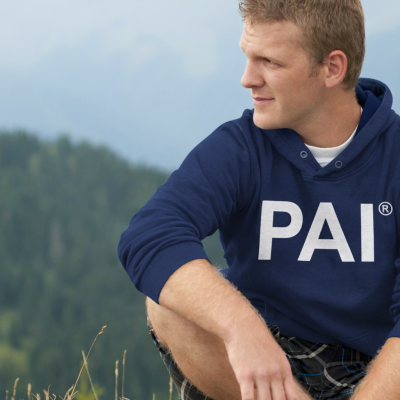 Homem sentado ao ar livre com capuz azul PAI e calça xadrez