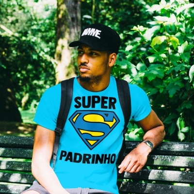 Homem sentado num banco de parque com t-shirt azul e boné preto