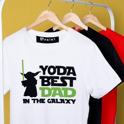 Três t-shirts em cabides, branca com texto e figura de Yoda, preta e vermelha no fundo