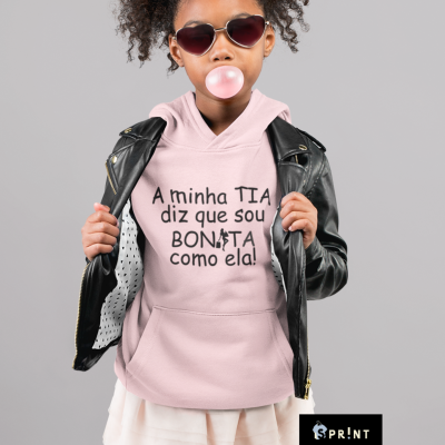 Criança com hoodie rosa e casaco de cabedal preto, com óculos escuros, a fazer bolha com pastilha elástica.