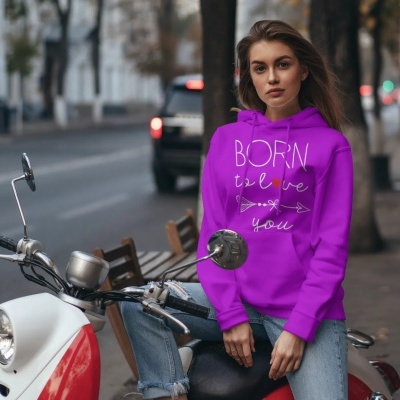 Mulher com casaco com capuz roxo com texto sentado numa scooter branca e vermelha na rua