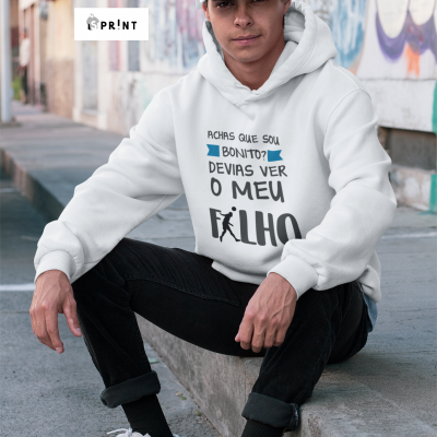 Homem jovem sentado com casaco de capuz branco com texto azul e preto na rua com paredes grafitadas