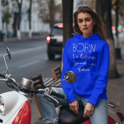 Mulher com casaco azul BORN to love you, sentada numa mota branca e vermelha na rua