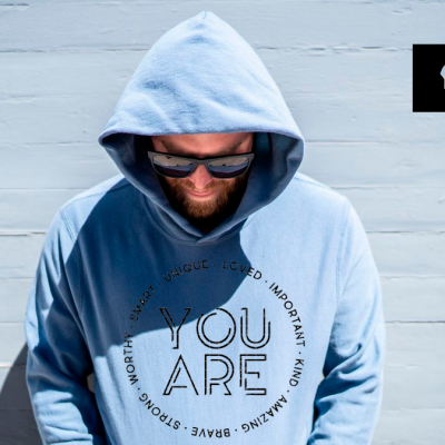 Sweatshirt azul claro com capuz e texto em preto, modelo com óculos escuros, fundo parede clara