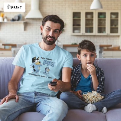 Homem com t-shirt azul clara estampada e menino sentado no sofá a comer pipocas