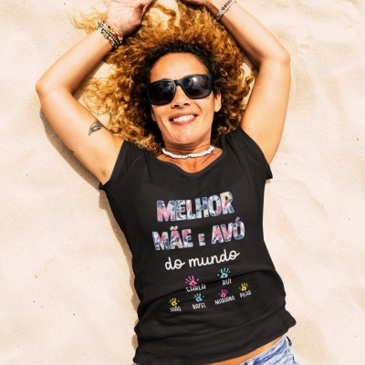 Mulher deitada na areia com t-shirt preta e óculos de sol