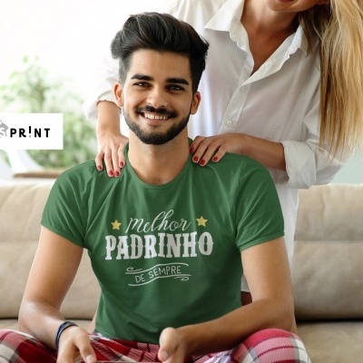 Homem sorridente de camiseta verde com texto, sentado no sofá com mulher atrás