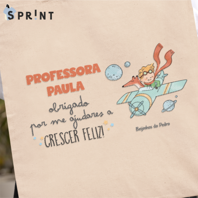 Saco de tecido bege com ilustração de menino num avião e texto de agradecimento a professora