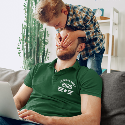 Homem com camisola polo verde com texto 'ORIGINAL SINCE 2020' e criança tapando-lhe os olhos