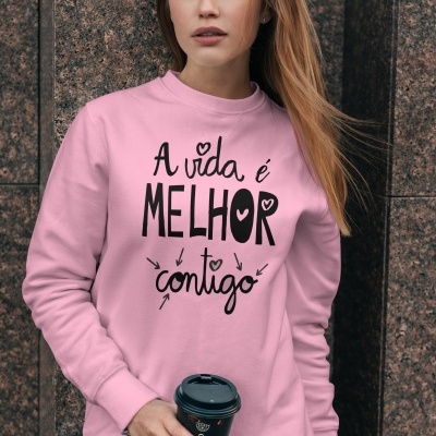 Mulher com sweat rosa claro com texto 'A vida é MELHOR contigo' segurando copo de café preto