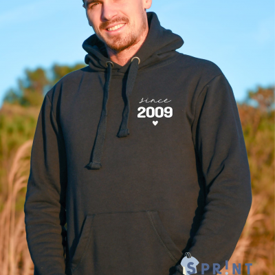 Homem com sweatshirt preta com capuz e estampa 'since 2009' ao ar livre