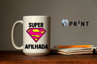 Caneca branca com símbolo do Super-Homem e frase SUPER AFILHADA ao lado de caderno e lápis