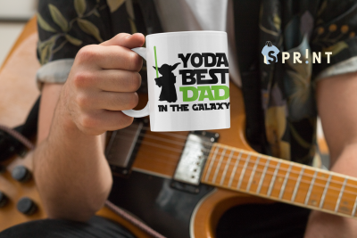 Caneca branca com texto YODA BEST DAD IN THE GALAXY numa mão, pessoa com guitarra ao fundo