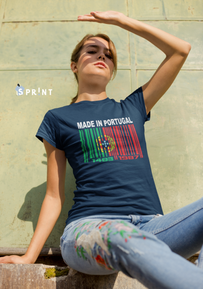 Mulher usando t-shirt azul escura 'MADE IN PORTUGAL' com código de barras colorido, sentada com jeans estampados