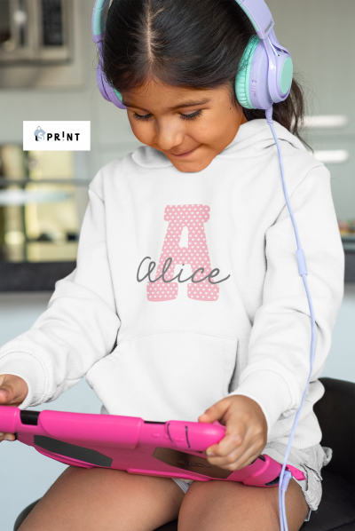 Menina com camisola branca personalizada com letra A rosa e nome Alice, auscultadores lilás e tablet rosa