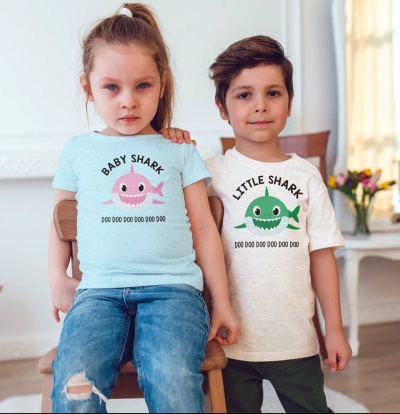 Crianças com t-shirts de desenho de tubarão e texto BABY SHARK e LITTLE SHARK em sala clara
