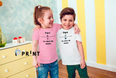 Duas crianças com t-shirts impressas com texto em preto num quarto colorido