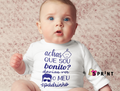 Bebé com roupa branca e texto azul sentado em superfície rosa macia.