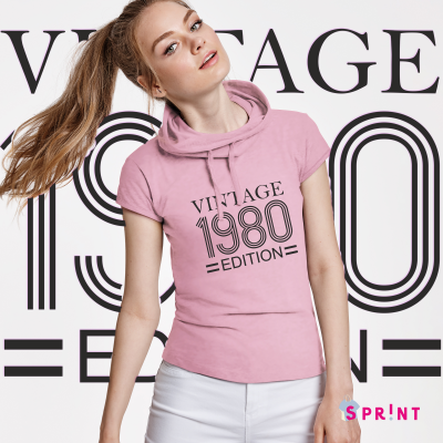 T-shirt rosa com capuz estampada 'VINTAGE 1980 EDITION' usada por mulher com calças brancas