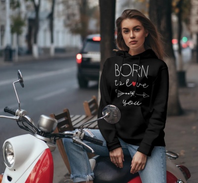 Mulher jovem sentada numa mota, usando sweatshirt preta com texto 'BORN to love you'