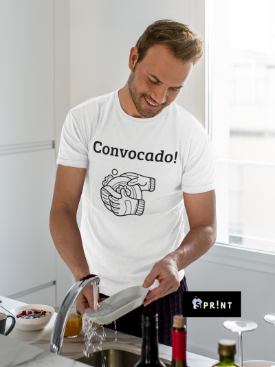 Homem a lavar prato com camiseta branca 'Convocado!' e ilustração de mãos na cozinha