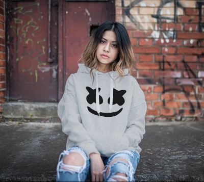 Moça sentada no chão com camisola cinzenta com estampa preta e jeans desfiados