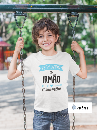 Criança com camiseta branca ao ar livre num parque, segurando correntes de baloiço.