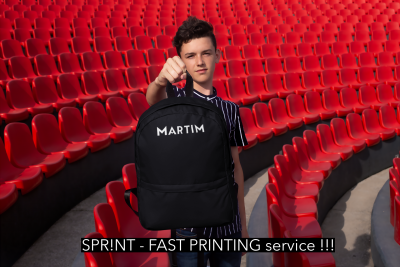Rapaz com mochila preta personalizada num estádio com cadeiras vermelhas