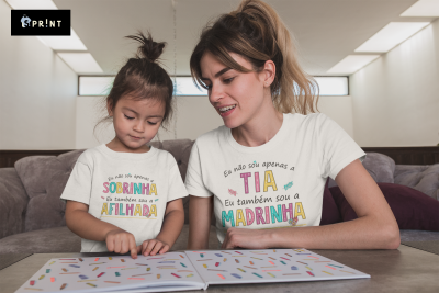 Camisetas brancas com texto colorido com frases familiares, criança e mulher sentadas a ler livro numa sala.