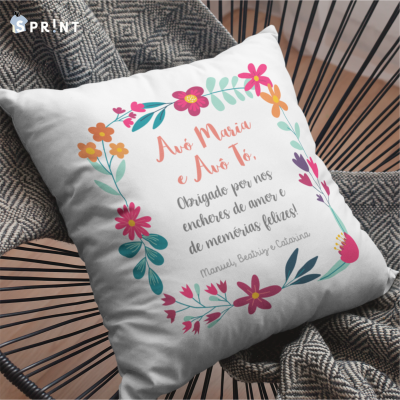 Almofada branca com flores coloridas e texto em português sentada em cadeira de metal preta com manta cinza