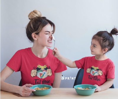 Duas t-shirts vermelhas, para mãe e filha, com desenho e texto, pessoas a partilhar refeição à mesa