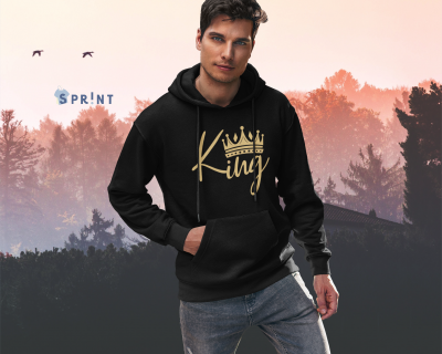 Homem com hoodie preto 'King' em fundo de árvores ao entardecer