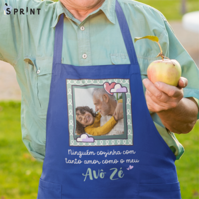 Avental azul com foto de avô e neto e texto personalizado, usado por pessoa com camisa verde e segurando maçã.