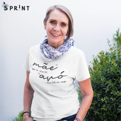 Mulher usando camiseta branca com texto 'mãe desde 1985 avó desde 2015' e lenço azul e branco