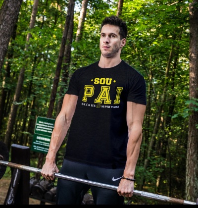 Homem com t-shirt preta com texto amarelo e branco em floresta