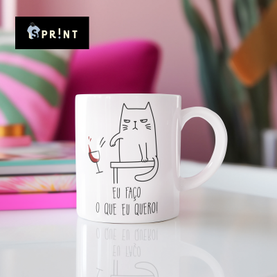 Caneca branca com desenho de gato e texto em português sobre mesa branca