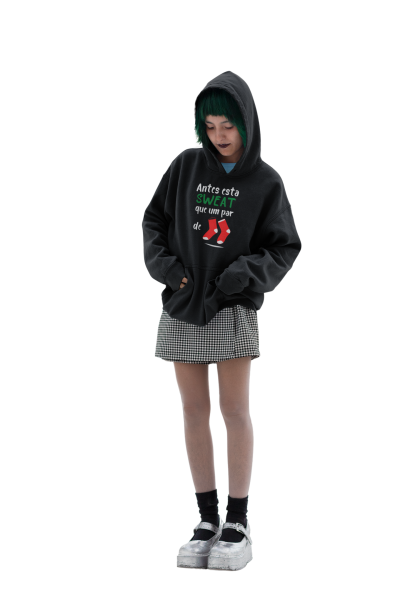 Moça jovem de hoodie preto com texto e padrões, saia pied-de-poule e sapatos brancos