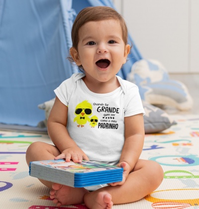 Bebé sentado com body branco estampado com dois pintainhos amarelos e texto em português