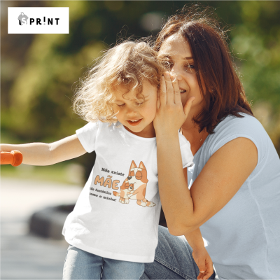 Criança com t-shirt branca estampada com desenho de cão e texto, com mulher ao lado em ambiente exterior