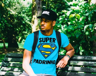 Homem sentado num banco de parque com t-shirt azul e boné preto