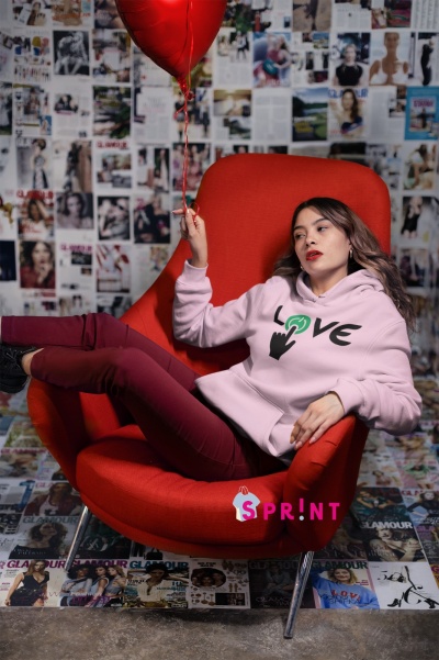 Mulher com hoodie LOVE rosa numa cadeira vermelha com balão de coração vermelho