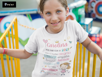 Camisola branca com design colorido e texto personalizado usada por rapariga num parque de diversões.