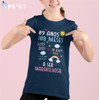 Camiseta azul escura com texto colorido e desenhos, vestida por criança sobre fundo rosa