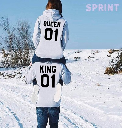 Casacos de capuz cinza com inscrições 'QUEEN 01' e 'KING 01' em preto, usados por casal na neve, céu azul e palavra 'SPRINT' rosa ao fundo.