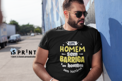 Homem com t-shirt preta com texto em português encostado numa parede azul